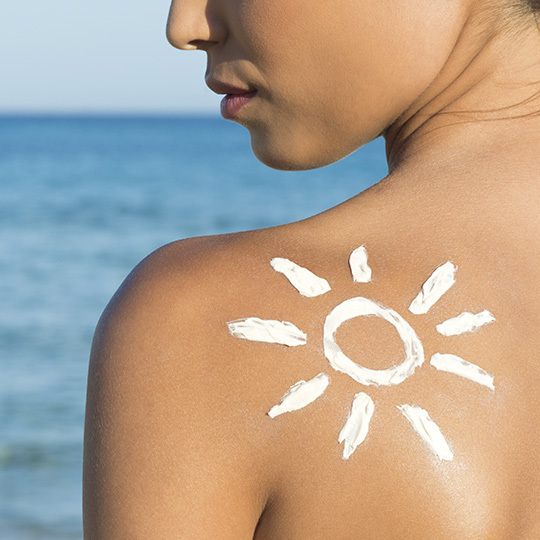 Eine Frau am Strand, die sich mit Sonnencreme einreibt